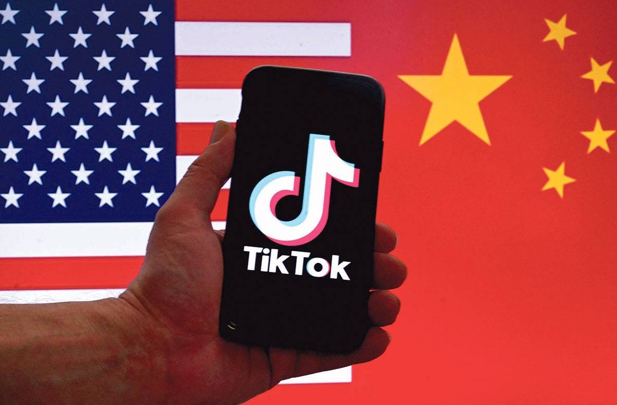 In this photo illustration, the logo of TikTok is displayed on the screen of an iPhone in front of a US flag and a Chinese in Washington, DC, on March 16, 2023. Photo by OLIVIER DOULIERY / AFP